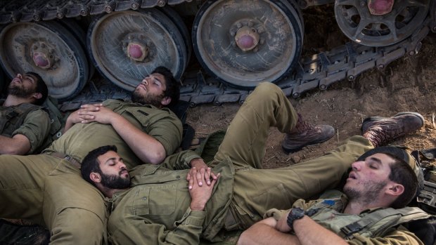 Israeli soldiers sleep next to armored personnel carriers at Sderot, near the Israeli-Gaza border on Tuesday.
