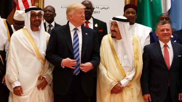 President Donald Trump talks with Saudi King Salman as they pose for photos with leaders at the Arab Islamic American Summit.