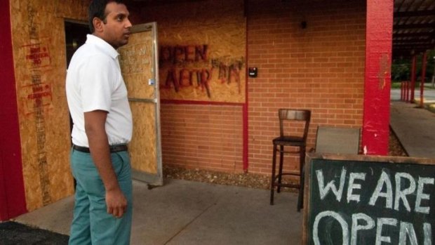 Resilient: Varun Madaksira, owner of the Original Red's BBQ in Ferguson, Missouri, pauses in front of his shop after helping a customer with an order.