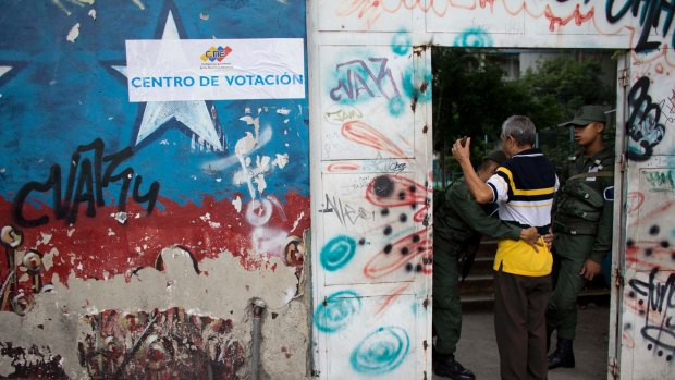 A National Guard soldier frisks a man before allowing him inside a polling station during regional elections in Caracas on Sunday.