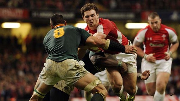 Wales' winger George North (C) is tackled by South Africa's prop Tendai Mtawarira (L) and Pierre Spies.