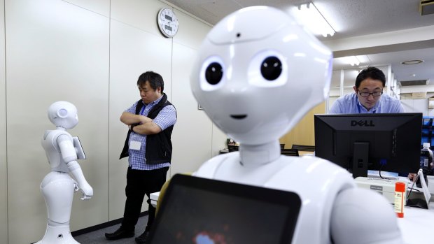 An employee, left, interacts with Pepper the humanoid robot, manufactured by SoftBank Group Corp., at the Orange Arch Inc. offices in Tokyo, Japan, on Monday, Oct. 5, 2015. Robots are everywhere. There are already 1.6 million of them, an army of disembodied limbs working in our factories to make everything from cars to pancakes. Now billionaire Masayoshi Son, chairman and chief executive officer of SoftBank, wants to bring robots into our homes. Photographer: Tomohiro Ohsumi/Bloomberg