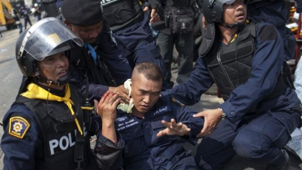 Police help a fellow officer injured by a grenade thrown by anti-government protesters in Bangkok.