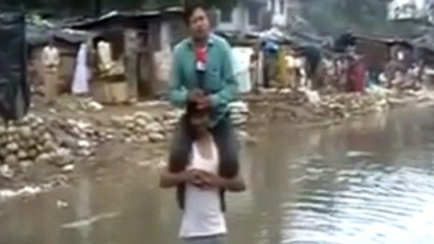 Reporter Narayan Pargaien, of  the News Express channel, sits on the shoulders of a flood victim.