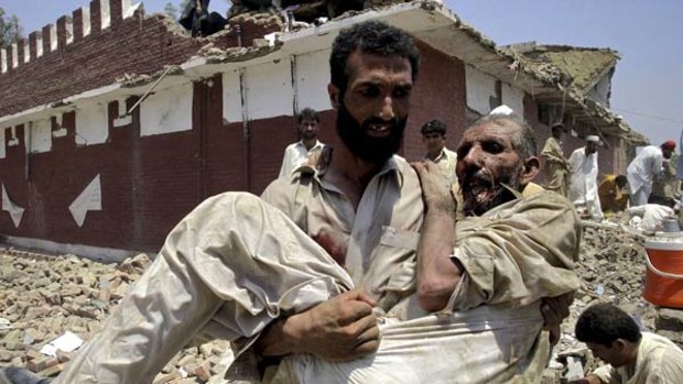 A Pakistani villager carries an injured person at the site of bombing in Yakaghund in Pakistani area of Mohmand.