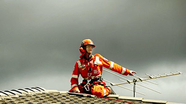 An SES volunteer secures and replaces tiles on a storm-damaged roof in Scoresby.
