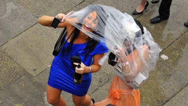 Race fans take shelter from the rain at Flemington.