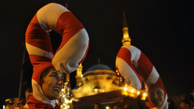 Lebanese performers dressed in candy costumes dance in front of Muhammad al-Amin Mosque during Christmas celebrations at Martyr's Square in Downtown Beirut, Saturday, Dec. 17, 2016. (AP Photo/Bilal Hussein)