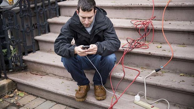 Plugged in ... a man charges his phone from a home that did not lose power in Hoboken, New Jersey.