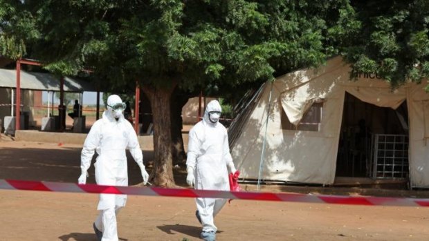 Health workers walk towards an area used for Ebola quarantine after they worked with diseased Fanta Kone at a Ebola virus centre in Mali.