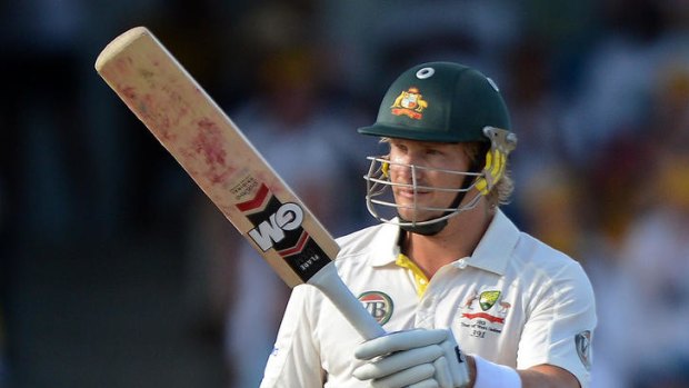 Australian cricketer Shane Watson rises his bat after completing his half century.
