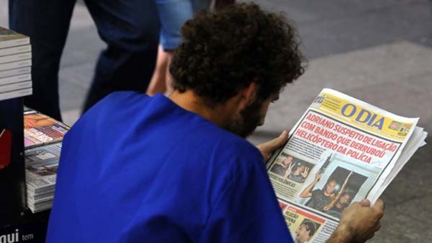 Wielding a gun ... a man reads a story on Brazilian striker Adriano on the front page of the Brazilian newspaper O Dia.