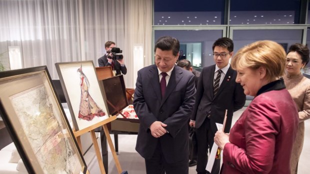 German Chancellor Angela Merkel presents Chinese President Xi Jinping with a map of China from the 18th century in Berlin, Germany. 