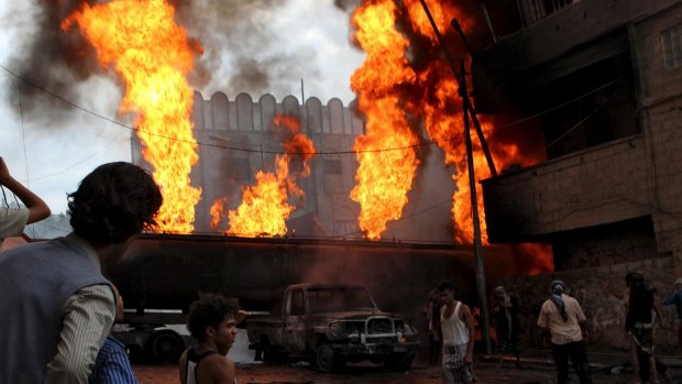 People look at a burning fuel truck after it was set ablaze during clashes between Houthis and fighters of the Popular Resistance Committees in Taiz, Yemen on Monday.