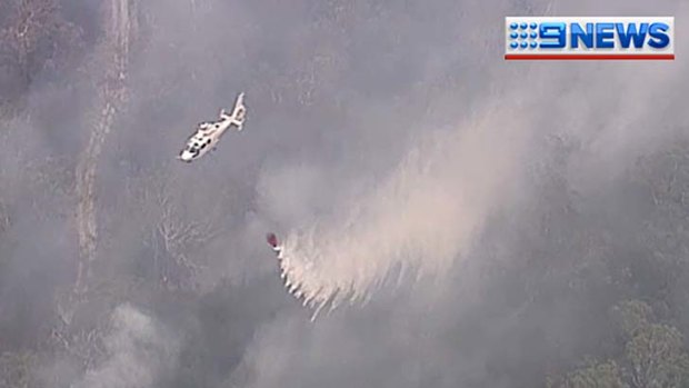 A helicopter water bombs the bushfire on North Stradbroke Island.