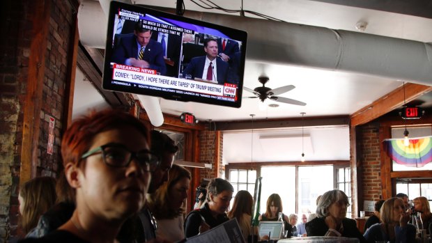 People watch live television broadcast of Mr Comey testifying in a Washington DC bar. 