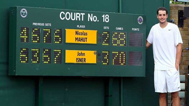 John Isner stands next to the scoreboard after beating Nicolas Mahut in last year's marathon match at Wimbledon.