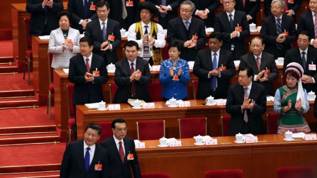 Members of the National People's Congress applaud as President Xi Jinping, front left, and Premier Li Keqiang, right, take their seats.