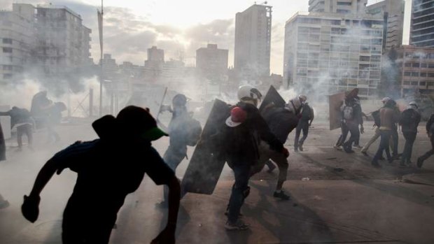 Demonstrators take cover from teargas fired by the police during clashes in Caracas on March 10.