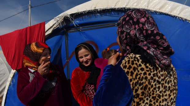 Friends Farah (left), Maryam (centre) holding her daughter, and Fatima celebrate their new-found freedom wearing bright coloured dresses after 2½ years of wearing black double veiled niqabs and gloves under Islamic State rule.