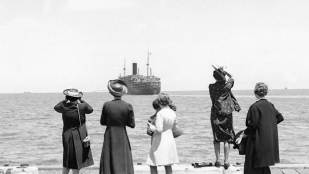 Women watch a troop transport ship depart.