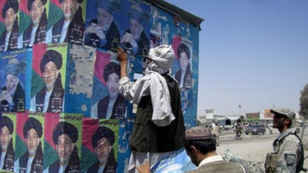Propaganda machine...supporters of Hamid Karzai plaster posters of the President on a wall near the border with Pakistan.