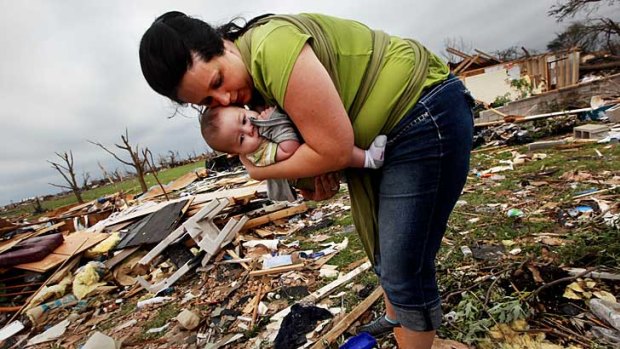 Amanda Carper holds her five-month-old son, Silas, as she searches through the rubble of her grandfather's home in Joplin, Missouri.