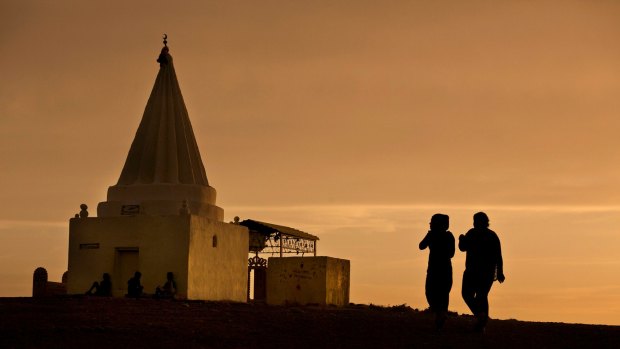 The sun sets as women visit a Yazidi shrine overlooking at Kankhe Camp for the internally displaced in Dahuk, northern Iraq, last year.