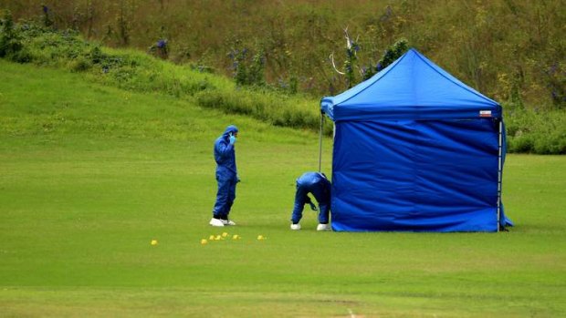 Grisly scene: officers look for evidence on the oval where the body was found.
