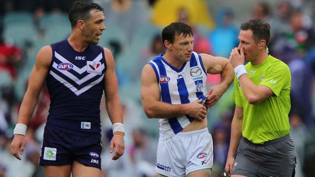 Kangaroo Brent Harvey talks to a field umpire about the attention he received from Fremantle's Ryan Crowley.