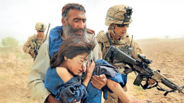 US marines follow in support as a young girl is carried by her father to a helicopter near Marja. The girl was injured when the marines were attacked at the weekend.
