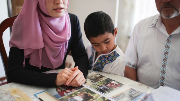 In Adelaide, a five-year-old boy views photos of relatives that have gone missing or are in Uighur internment camps.