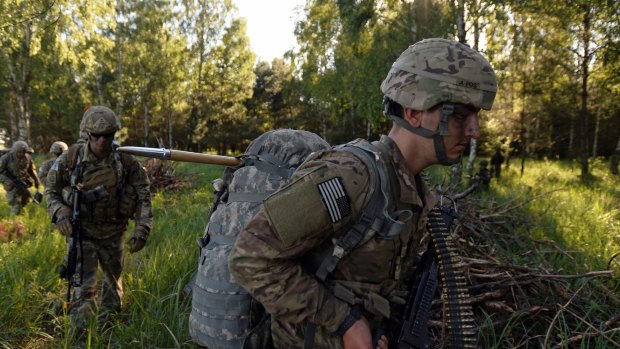 Paratroopers from the U.S. 82nd Airborne Division walk to their positions after conducting a a multi-national jump with British and Polish soldiers.