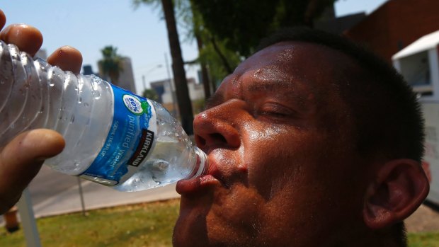 Phoenix man Steve Smith tries to keep hydrated as temperatures climb to near-record highs.