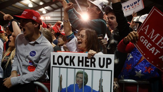 Supporters of Republican presidential candidate Donald Trump, one holding a sign that reads, "LOCK HER UP," cheer during a campaign rally in Leesburg, Virginia in November 2016. 