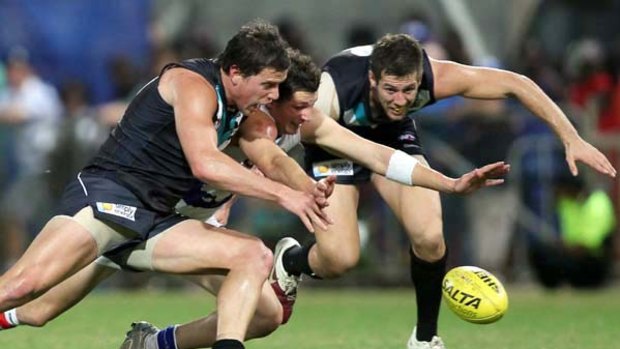 Port Adelaide's Chris Salter and Steven Salopek put the squeeze on Bulldog Andrejs Everitt in their fight for the ball last night.