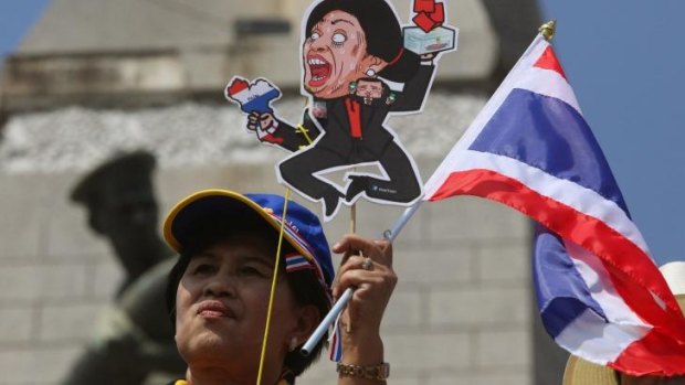No joke: An anti-government protester holds a cartoon cut-out of Thailand's Prime Minister Yingluck Shinawatra during a rally at Victory Monument in Bangkok.