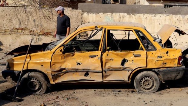 Widespread destruction: An Iraqi taxi driver inspects his damaged car after a car bomb attack on Sinaa Street in downtown Baghdad.