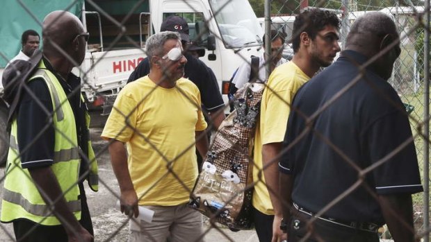 Two injured asylum seekers at Manus Island airport leave for Port Moresby on Thursday following riots at the detention centre.