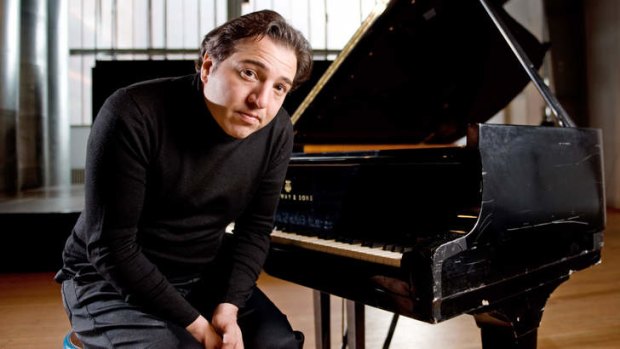 Turkish pianist Fazil Say posing in front of a piano