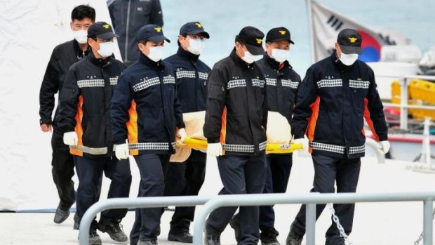 Grim task: South Korea rescue members carry the body of a victim recovered from the ferry to an ambulance.