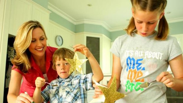 Tara Dennis helps Byron O'Mahony and sister Sarelle make glitter star Christmas ornaments.