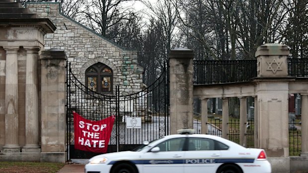 A police car patrols in front of Chesed Shel Emeth Cemetery in University City, Missouri.