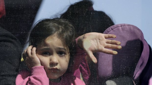 A girl looks out of  a bus window after her arrival by ferry with hundreds of other migrants and refugees to the port of Elefsina, west of Athens.