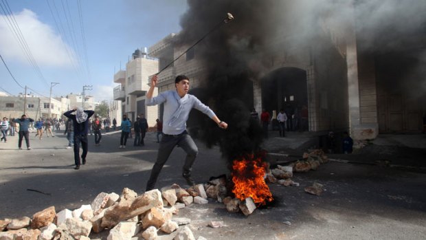 A Palestinian protester uses a slingshot to hurl stones towards Israeli security forces during clashes in the village of Saair, east the West Bank city of Hebron, following the death of a Palestinian prisoner held in Israel.