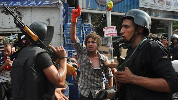 A supporter of ousted Islamist President Mohamed Mursi raises his arm as Egyptian security forces detain him at a sit-in camp set up near Cairo University.