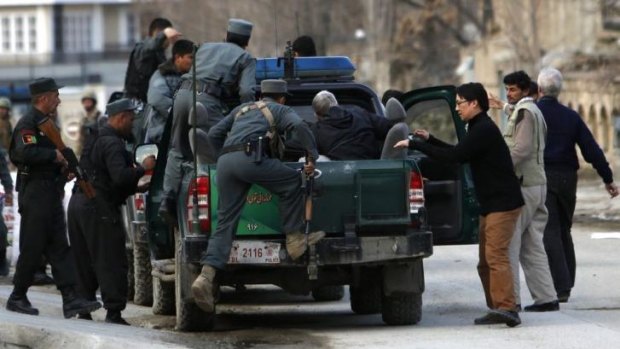 US charity targeted: Afghan policemen evacuate foreigners from the site of the attack.