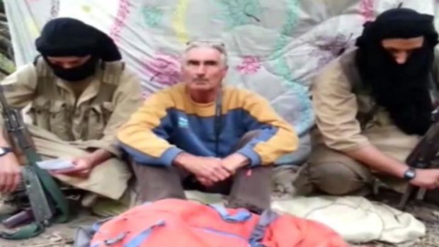 An image grab taken from a video released by Jund al-Khilifa group video, allegedly shows French tourist, Herve Pierre Gourdel, sitting between two armed jihadists at an undisclosed location. 