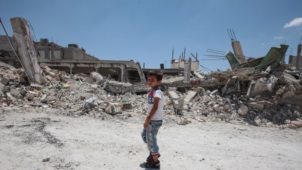 A boy walks past destroyed buildings in the Syrian town of Kobane.