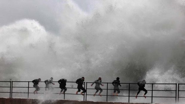 Wall of water warriors ... a group of boys in wet suits take on the rough seas lashing Wollongong Harbour’s breakwall. It has been the wettest July in more than 60 years.